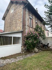 a brick house with a white garage door and flowers at Jolie Meulière à 15 min de Paris in Deuil-la-Barre