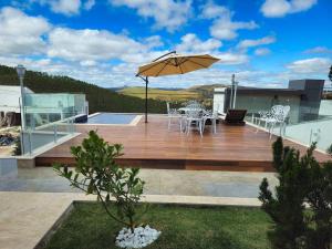 a wooden deck with an umbrella on top of a house at MANSÃO Casablanca in Nova Lima