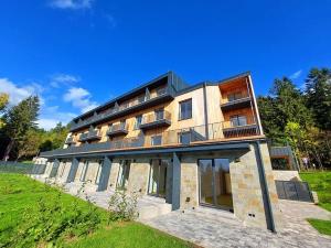a large building on top of a green field at Horský apartmán s možností wellness Benecko by AlkaTravel in Benecko