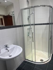 a shower with a glass door next to a sink at Self contain studio with room, double bed, kitchen in London +2 photos