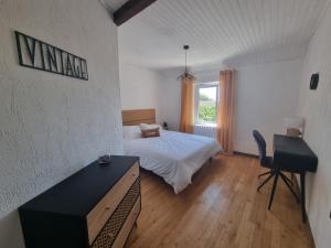 a bedroom with a bed and a desk and a television at L'Oustau de Maître Potager in Valréas