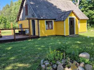 a yellow house with a porch and a yard at Kalda Puhkemaja in Helmküla