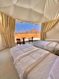 a bedroom with a large white bed and a table at Ammura rum camp in Wadi Rum