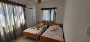 two twin beds in a room with windows at King Philips in Paphos