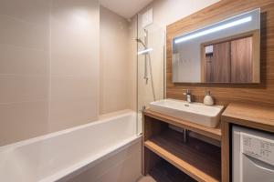 een badkamer met een wastafel, een bad en een spiegel bij Apartment SCHLADMING - Planai view in Schladming +22 foto's