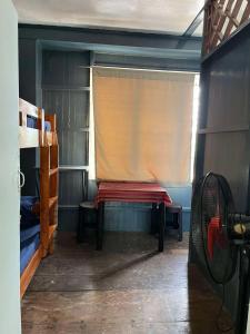 een kamer met een raam met een gordijn en een bank bij Backpacker's Lodge - Fan Room 1 in Bacnotan