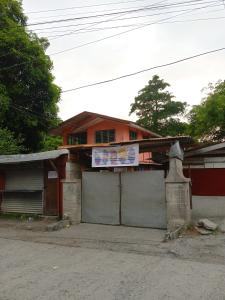 een huis met een bord erop bij Backpacker's Lodge - Fan Room 1 in Bacnotan