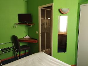 a green room with a bed and a desk and a television at Hotel De Provence in Digne-les-Bains