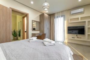 Un dormitorio con una gran cama blanca y un televisor de pantalla plana. en Villa Hodaj 2, en Afantou