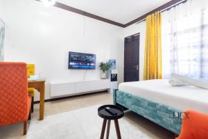 a bedroom with a bed and a desk and a tv at Marahaba Cozy Studio Nyali in Mombasa