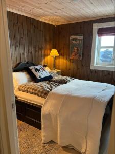 ein Schlafzimmer mit einem Bett in einer Holzwand in der Unterkunft Ullsheim Grendehytte in Beitostøl
