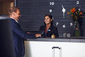 a man and a woman shaking hands at a counter at Sky Hotel Apartments, Stockholm in Stockholm