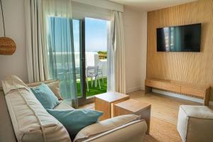 Una sala de estar con un sofá y un televisor. en Punta Candor Suites, en Rota
