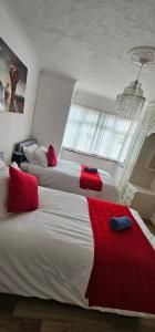 a bedroom with two beds with red pillows and a window at Contractors Home from Home in South Benfleet +8 photos