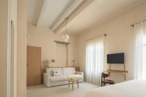 ein Schlafzimmer mit einem Bett, einer Couch und einem Tisch in der Unterkunft Moshoviti Residence in Rethymno