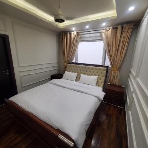 a bedroom with a large white bed with a window at Executive 2BHK Apt in Elysium tower Isb in Islamabad