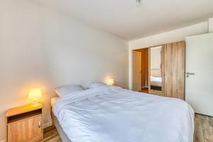 ein Schlafzimmer mit einem großen weißen Bett und einem Nachttisch in der Unterkunft Moulin à Vent A14 - Appt pour 4 avec balcon in Bondy