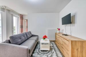 ein Wohnzimmer mit Sofa und Flachbildfernseher in der Unterkunft Moulin à Vent A21 - Appt pour 4 in Bondy