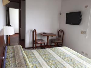 a bedroom with a bed and a table and a tv at Hotel Libertadores in Paipa