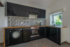- une cuisine avec des armoires noires et un lave-linge dans l'établissement Maisonnette de charme, à La Colle-sur-Loup