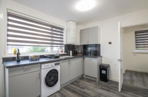 a kitchen with white cabinets and a washer and dryer at An Elegant 3 Bedroom House in Aberdeen