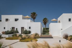 a white building with palm trees in front of it at Parilio, a Member of Design Hotels in Naousa