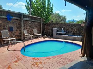 a small swimming pool with chairs and a table at Maroela Gardens Guesthouse in Thabazimbi