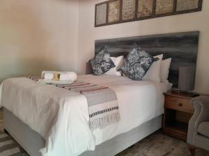 a bedroom with a large white bed with pillows at Maroela Gardens Guesthouse in Thabazimbi