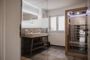 a bathroom with a sink and a glass door at Gutzeit-Appartements mit privater Infrarotkabine in Bad Hindelang