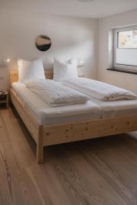 a bedroom with a wooden bed with white sheets and pillows at Gutzeit-Appartements mit privater Infrarotkabine in Bad Hindelang