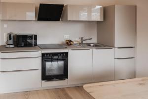 a white kitchen with a sink and a stove at Gutzeit-Appartements mit privater Infrarotkabine in Bad Hindelang
