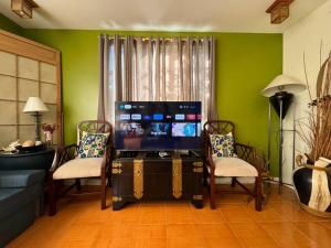 a living room with a tv and two chairs at Cozy Family Home near Nuvali & Tagaytay with wifi in Santa Rosa