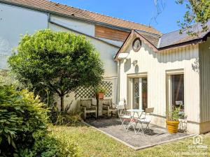 a house with a table and chairs in the yard at Ô fil de l'eau - Jardin, Cabanon d'Antan, Parking in Olivet