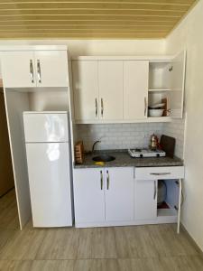 a kitchen with white cabinets and a white refrigerator at Göksel Apart in Mersin