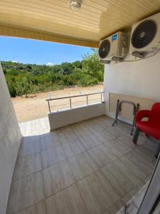 a room with a balcony with a red chair and a television at Göksel Apart in Mersin