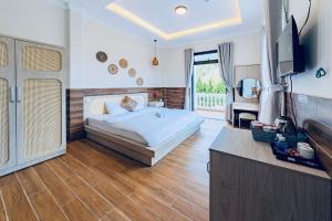 a bedroom with a bed and a television in it at White Villa Đà Lạt in Da Lat