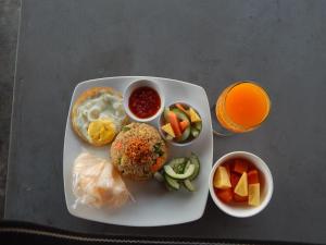 a plate of food with fruit and a glass of orange juice at Rosella Cottages - Homestay - Yogyakarta in Yogyakarta