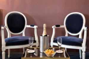 - deux chaises avec une bouteille de champagne et une table avec des verres à vin dans l'établissement Hotel De Clisson Saint Brieuc, à Saint-Brieuc