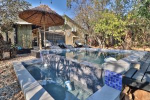 a pool with an umbrella and some chairs and a table at shiringa holiday home in Marloth Park