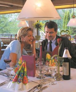 a man and woman sitting at a table with a laptop at Ferienwohnungen Kurhotel Eichinger in Bad Wörishofen