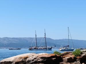 three boats floating on the water with mountains in the background at Casa Beatriz in Cambados