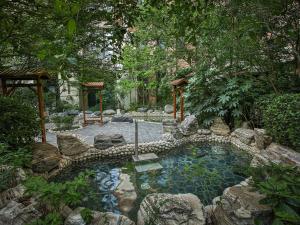 een zwembad in een tuin met rotsen en bomen bij Swissotel Xi' an Xinxing Hot Spring in Xi'an