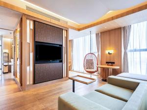 een woonkamer met een bank en een flatscreen-tv bij Swissotel Xi' an Xinxing Hot Spring in Xi'an