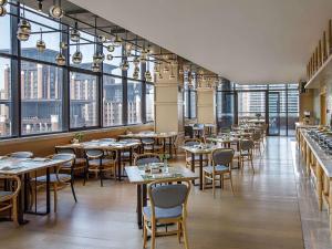 een restaurant met tafels en stoelen en grote ramen bij Swissotel Xi' an Xinxing Hot Spring in Xi'an