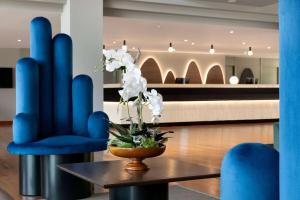 een lobby met blauwe stoelen en een tafel met witte bloemen bij Dolce by Wyndham Barcelona Resort in Sant Esteve Sesrovires