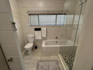a bathroom with a tub and a toilet and a shower at No 1 on Springfield in Winterton +13 photos
