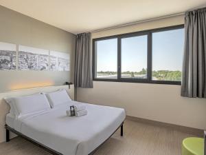 sypialnia z białym łóżkiem i dużym oknem w obiekcie B&B HOTEL Bologna w mieście Castel Maggiore