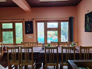 a dining room with a table and chairs and windows at Sangay Guest House Leh-Ladakh By LexStays in Leh