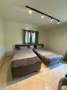 zwei Betten in einem Schlafzimmer mit Deckenbeleuchtung in der Unterkunft A Suites Apartments Faraya in ‘Ayn Barq
