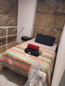 a bed with a colorful blanket and a hat on it at Casa Augusta AL in Braga